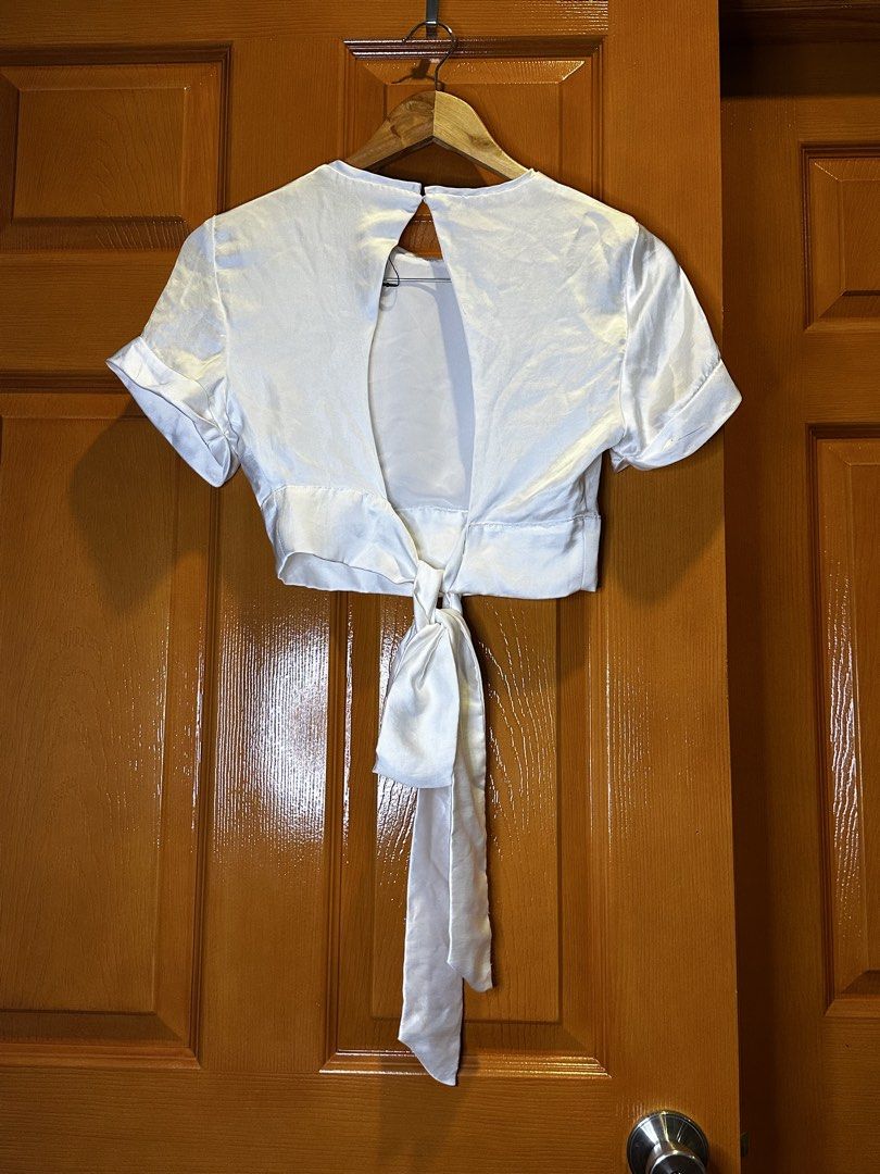 Zara White Satin Cropped Tie Back Top Medium (Category: Blouses) located in Angeles City. Submitted by luxenstuff (Listing ID 1461234057, Image 2). Description: - Zara white satin cropped top - Elegant tie-back strap detail - Short sleeves with stylish cuffed hems - Length: 13 inches - Bust (armpit to armpit): 29 inches - Sleeve length: 7 inches Kept Unused with minor pen mark on the back sleeve check photo.