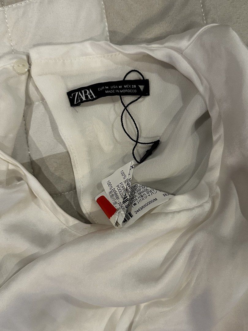 Zara White Satin Cropped Tie Back Top Medium (Category: Blouses) located in Angeles City. Submitted by luxenstuff (Listing ID 1461234057, Image 3). Description: - Zara white satin cropped top - Elegant tie-back strap detail - Short sleeves with stylish cuffed hems - Length: 13 inches - Bust (armpit to armpit): 29 inches - Sleeve length: 7 inches Kept Unused with minor pen mark on the back sleeve check photo.