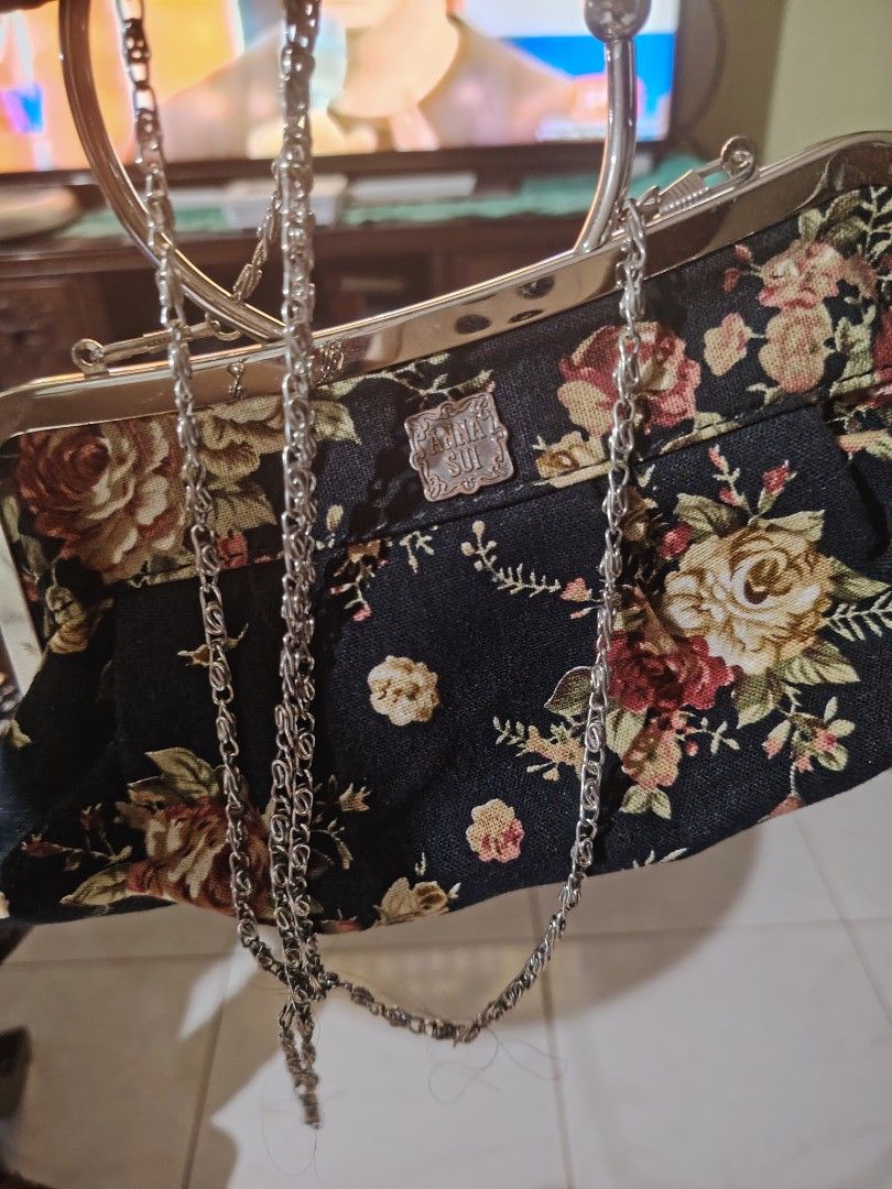 Anna Sui Floral Clutch Bag with Chain Strap (Category: Clutches) located in Luisiana. Submitted by sahayamay77 (Listing ID 1461500515, Image 2). Description: - Cute Anna Sui clutch bag - Black base with red and cream floral print - Features a metal frame and ring handle - Includes a detachable silver chain strap - Interior zippered pocket - Ideal for evening wear and special occasions.