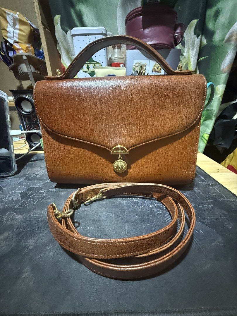 Aylesbury Brown Leather Handbag with Shoulder Strap (Category: Shoulder Bags) located in Opol. Submitted by great_finds_kollexion (Listing ID 1461334939, Image 1). Description: - Brand: Aylesbury - Material: Brown Leather - Features: Top handle, detachable shoulder strap - Interior: Lined with a small pocket - Hardware: Gold-tone with decorative charm - Style: Classic, perfect for everyday use.