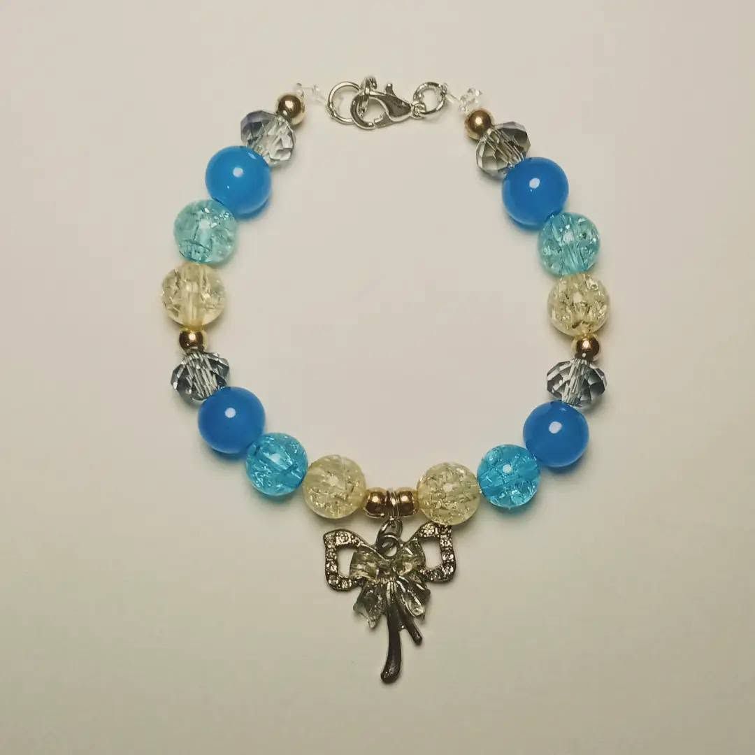 Blue Beaded Bracelet with Bow Charm (Category: Bracelets) located in Caloocan City. Submitted by dear_solace_trinkets (Listing ID 1461427274, Image 1). Description: - Cute beaded bracelet - Blue and clear crackle beads - Accented with gold and silver beads - Sparkly silver bow charm - Clasp closure - Adds a pop of color to any outfit.