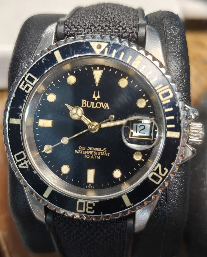 Bulova Automatic Swiss Made (1990s) (Category: Men's Watches) located in Quezon City. Submitted by jtgabs (Listing ID 1461441917, Image 2). Description: - 1990s Bulova watch with a classic black dial. - Features 25 jewels for precise timekeeping. - Water-resistant up to 10 ATM (100 meters) - Includes a functional rotating bezel and a convenient date window. - Comes with a stylish, textured rubber black strap. - Shows some signs of normal wear on 