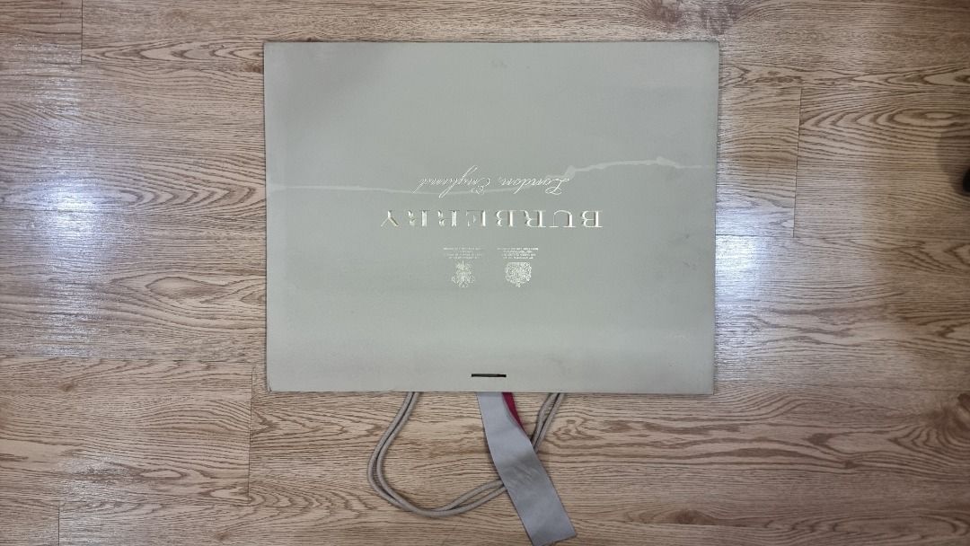Burberry Shopping Bag (Category: Luxury Bags & Wallets) located in Paranaque City. Submitted by olxph_668280920 (Listing ID 1461472236, Image 2). Description: - Authentic Burberry shopping bag - Color: Beige - Features gold embossed logo - Signature Burberry check pattern - Comes with red ribbon detail - Ideal for storing items or as a gift bag - Approximate dimensions: 15 inches wide x 12 inches tall exact size on blue papre.