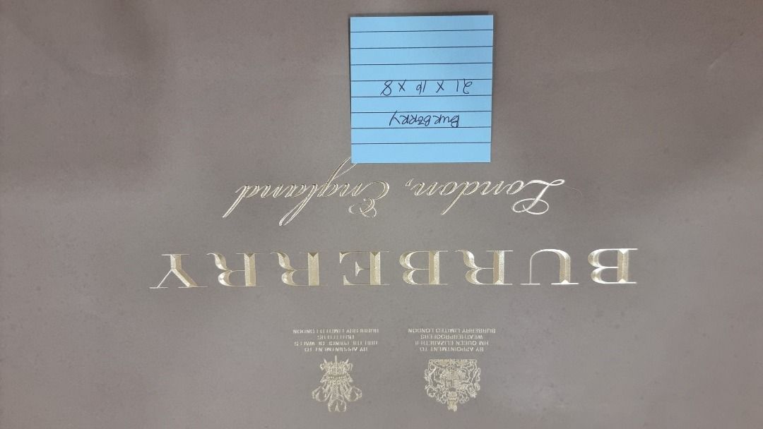 Burberry Shopping Bag (Category: Luxury Bags & Wallets) located in Paranaque City. Submitted by olxph_668280920 (Listing ID 1461472236, Image 3). Description: - Authentic Burberry shopping bag - Color: Beige - Features gold embossed logo - Signature Burberry check pattern - Comes with red ribbon detail - Ideal for storing items or as a gift bag - Approximate dimensions: 15 inches wide x 12 inches tall exact size on blue papre.