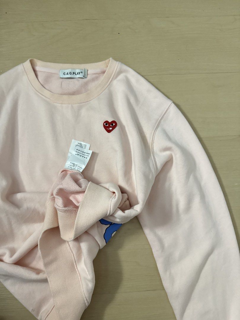 CDG PLAY Sweater (Category: Longsleeves) located in Manila. Submitted by juhjuh (Listing ID 1461380443, Image 2). Description: - Authentic Pink CDG PLAY Sweatshirt - Iconic heart logo on the front - Large 'CDG PLAY SCALDING' graphic print on the back - Classic crew neck and long sleeves - Comfortable and stylish for everyday wear - Good as new .