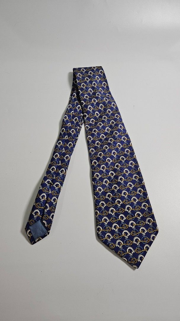 Celine Paris Pure Silk Tie Made in Spain (Category: Ties) located in Alfonso. Submitted by jbcamet (Listing ID 1461492986, Image 1). Description: - Authentic Celine Paris tie - 100% pure silk - Navy blue base with repeating gold, white, and blue horseshoe and rope motifs - Crafted in Spain - Perfect for formal or business occasions.