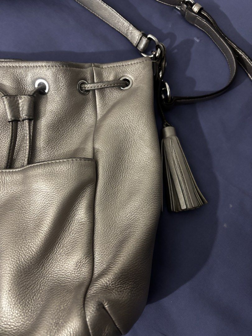 Coach Metallic Leather Drawstring Bucket Bag (Category: Luxury Bags & Wallets) located in Olongapo. Submitted by lovejeansph (Listing ID 1461363013, Image 2). Description: - Genuine leather Coach bucket bag - Cool metallic pewter color - Front slip pocket - Tassel detail - Adjustable strap for crossbody or shoulder wear - Spacious interior - Ideal for everyday use.