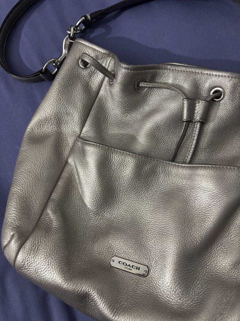 Coach Metallic Leather Drawstring Bucket Bag (Category: Luxury Bags & Wallets) located in Olongapo. Submitted by lovejeansph (Listing ID 1461363013, Image 3). Description: - Genuine leather Coach bucket bag - Cool metallic pewter color - Front slip pocket - Tassel detail - Adjustable strap for crossbody or shoulder wear - Spacious interior - Ideal for everyday use.