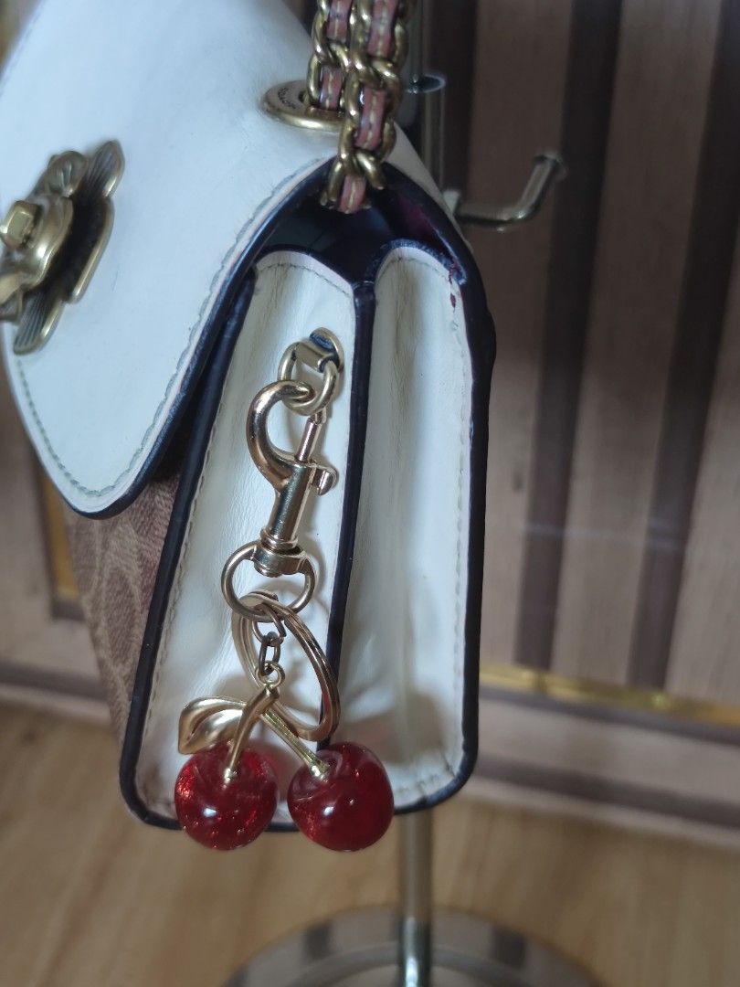 Coach Parker 18 Small, convertible bag (Category: Luxury Bags & Wallets) located in Dagupan City. Submitted by jhazrightshop (Listing ID 1461446049, Image 2). Description: - Coach crossbody bag - Signature print - White flap closure with gold flower detail - Adorable cherry charm included - Gold chain strap - Ideal for casual outings.