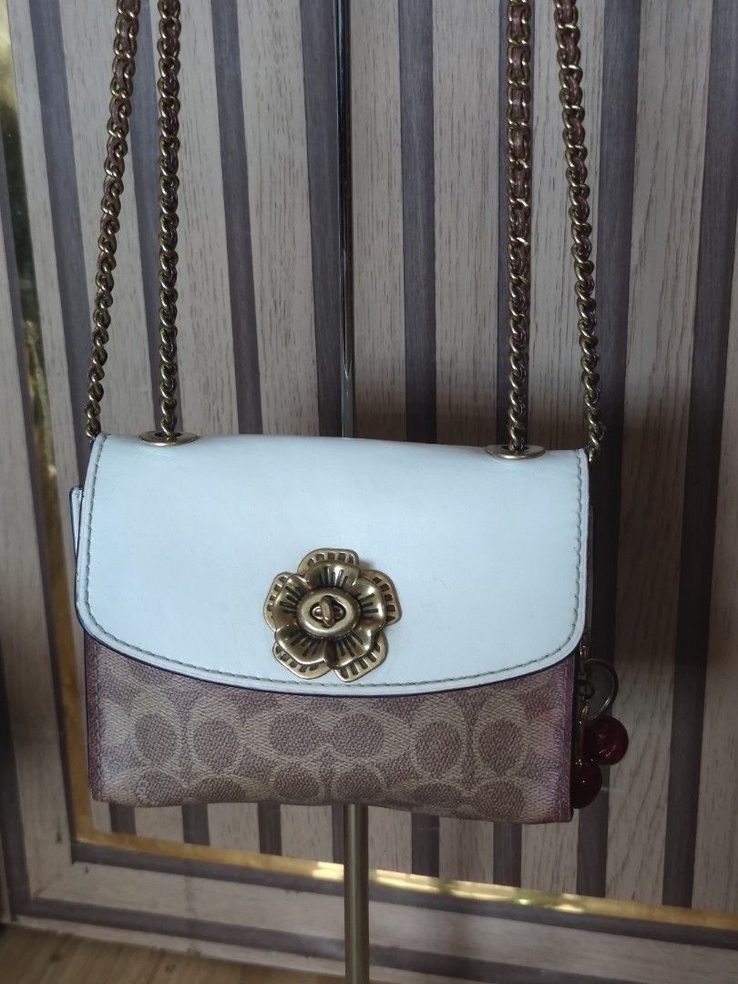 Coach Parker 18 Small, convertible bag (Category: Luxury Bags & Wallets) located in Dagupan City. Submitted by jhazrightshop (Listing ID 1461446049, Image 1). Description: - Coach crossbody bag - Signature print - White flap closure with gold flower detail - Adorable cherry charm included - Gold chain strap - Ideal for casual outings.