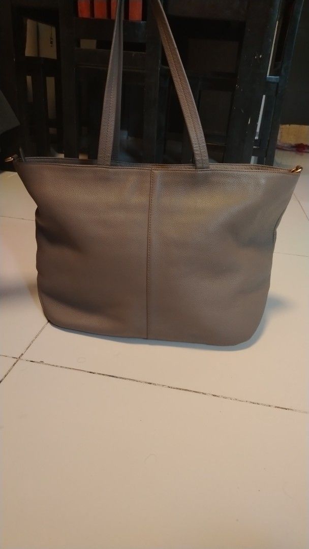 couronne Grey Leather Tote Bag (Category: Tote Bags) located in Manila. Submitted by wildwind_73f77a (Listing ID 1461482599, Image 3). Description: - Grey leather tote bag by Cole Haan - Spacious interior, ideal for everyday use - Features a textured leather finish - Gold-tone accent plate on the front - Comfortable handles for easy carrying - Simple and classic design.