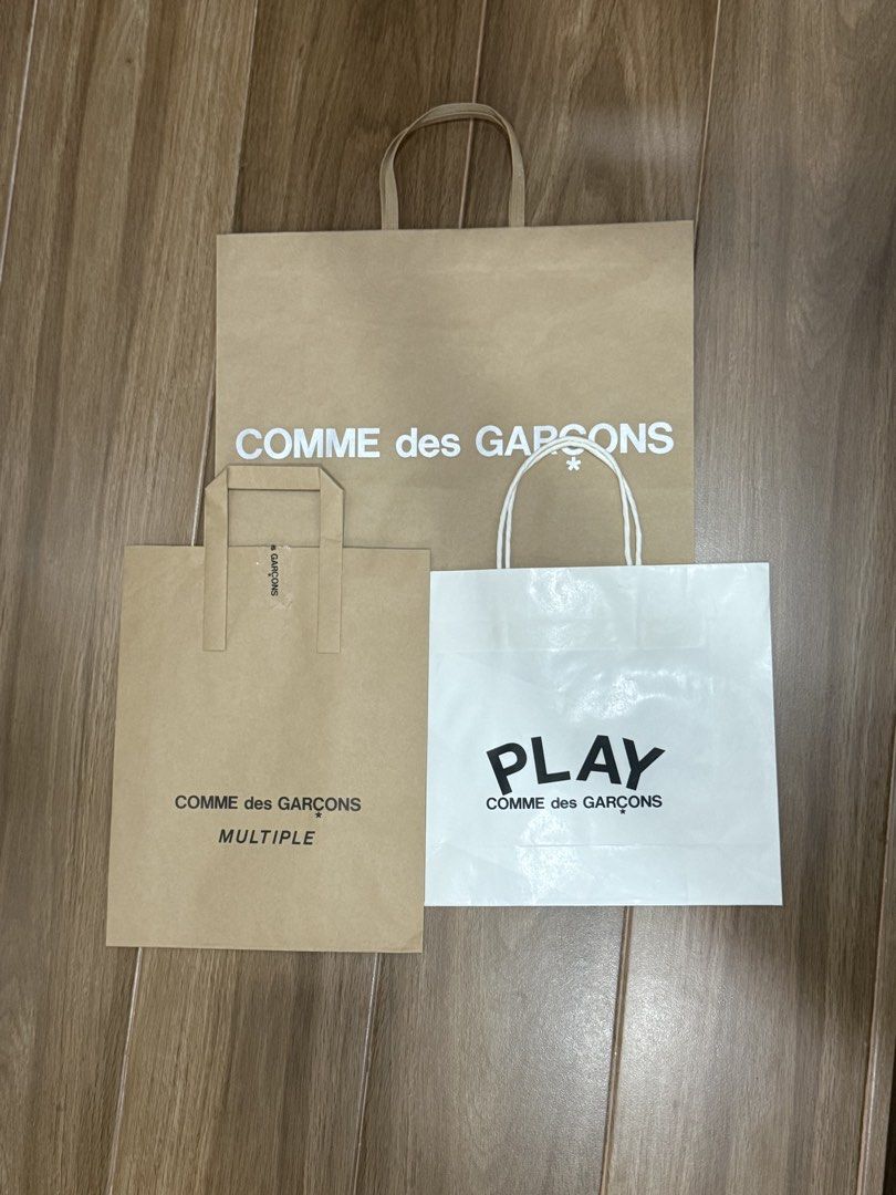 Comme des Garçons Shopping Bags (Category: Luxury Bags & Wallets) located in Cavite. Submitted by mjoy0302md (Listing ID 1461422645, Image 1). Description: - Bundle of 3 authentic Comme des Garçons shopping bags. - Includes one large brown bag with the classic 'COMME des GARCONS' logo. - Features a smaller brown bag with 'COMME des GARCONS MULTIPLE' text. - Comes with a white bag showcasing the 'PLAY COMME des GARCONS' logo. - Ideal for collector