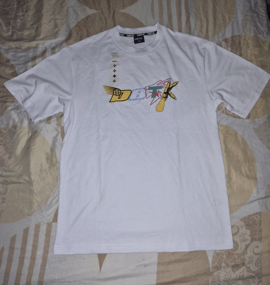 DBTK Oversized Tee White Graphic Print (Category: Tshirts & Polo Shirts ) located in Taguig. Submitted by chloe_clothingco. (Listing ID 1461369975, Image 1). Description: - White DBTK oversized t-shirt - Size: Large (L) - Unique graphic print on front and back - Designs include rocket, astronaut, and gaming themes - Comfortable fabric - Perfect for everyday casual style.