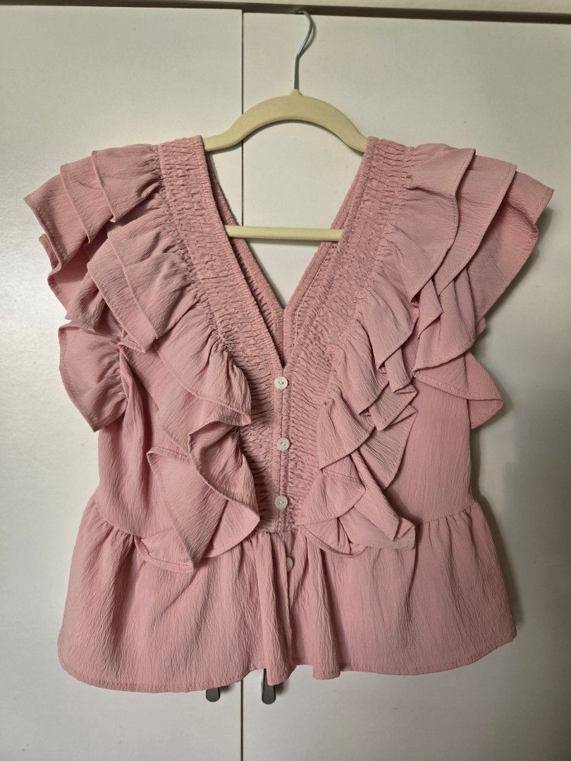 Deep V neckline top (Category: Blouses) located in Agdangan. Submitted by wearitnext.shop (Listing ID 1461454859, Image 3). Description: Dusty-pink sleeveless top with bold ruffle accents and peplum style flared hem. Size: Small to Medium.