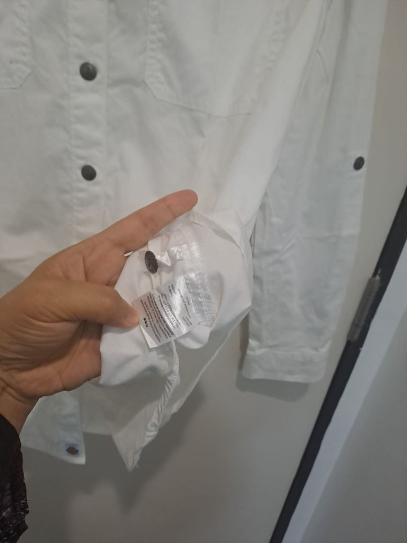 Dickies white linen cotton (Category: Longsleeves) located in Mandaluyong City. Submitted by epicowl-c93c (Listing ID 1461350245, Image 3). Description: The image shows a white Dickies utility work shirt designed for women. It features a classic collared neckline, a full button-down front with contrasting dark buttons, and two symmetrical chest patch pockets with buttoned flaps.The inner collar tag includes the brand logo and reads "Crafted for W