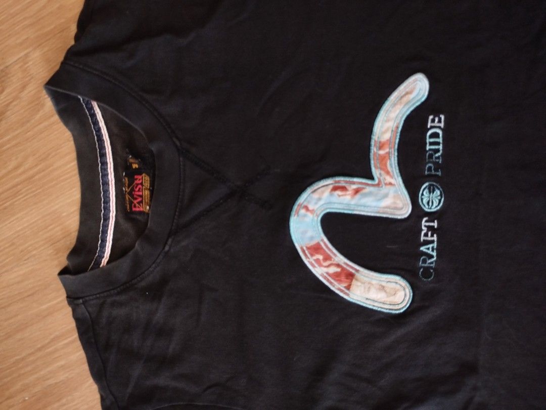 EVISU "Craft Pride" T-Shirt (Category: Tshirts & Polo Shirts ) located in Quezon City. Submitted by y2k_thriftkid (Listing ID 1461404370, Image 2). Description: - Authentic Black Evisu T-shirt - Iconic "Evisu" logo and "Craft Pride" text - Small Evisu tag detail on sleeve - Proudly Made in Japan - Ideal for everyday casual wear.