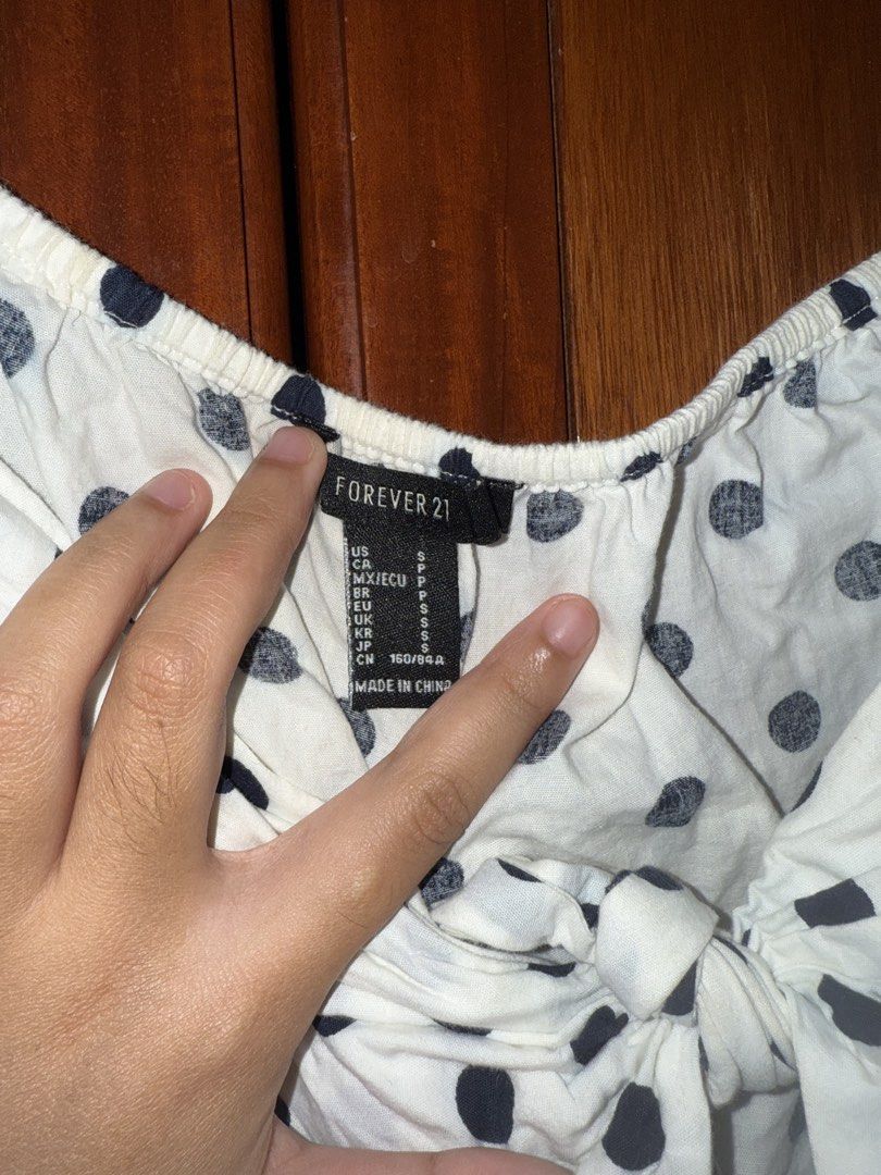 Forever 21 White Polka Dot Tie Front Crop Top (Category: Sleeveless) located in Taguig. Submitted by ksooos (Listing ID 1461407043, Image 3). Description: Cute white polka dot crop top with tie front and puff sleeves. Size S. - slight yellowing sa inner garter at the back. unseen if ure wearing it - rfs: i gained weight this is sooo cute 🥲 but it just doesnt fit me well anymore.