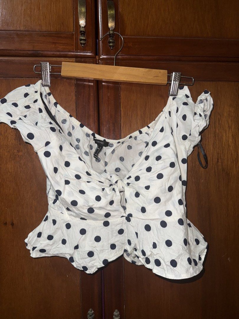 Forever 21 White Polka Dot Tie Front Crop Top (Category: Sleeveless) located in Taguig. Submitted by ksooos (Listing ID 1461407043, Image 1). Description: Cute white polka dot crop top with tie front and puff sleeves. Size S. - slight yellowing sa inner garter at the back. unseen if ure wearing it - rfs: i gained weight this is sooo cute 🥲 but it just doesnt fit me well anymore.