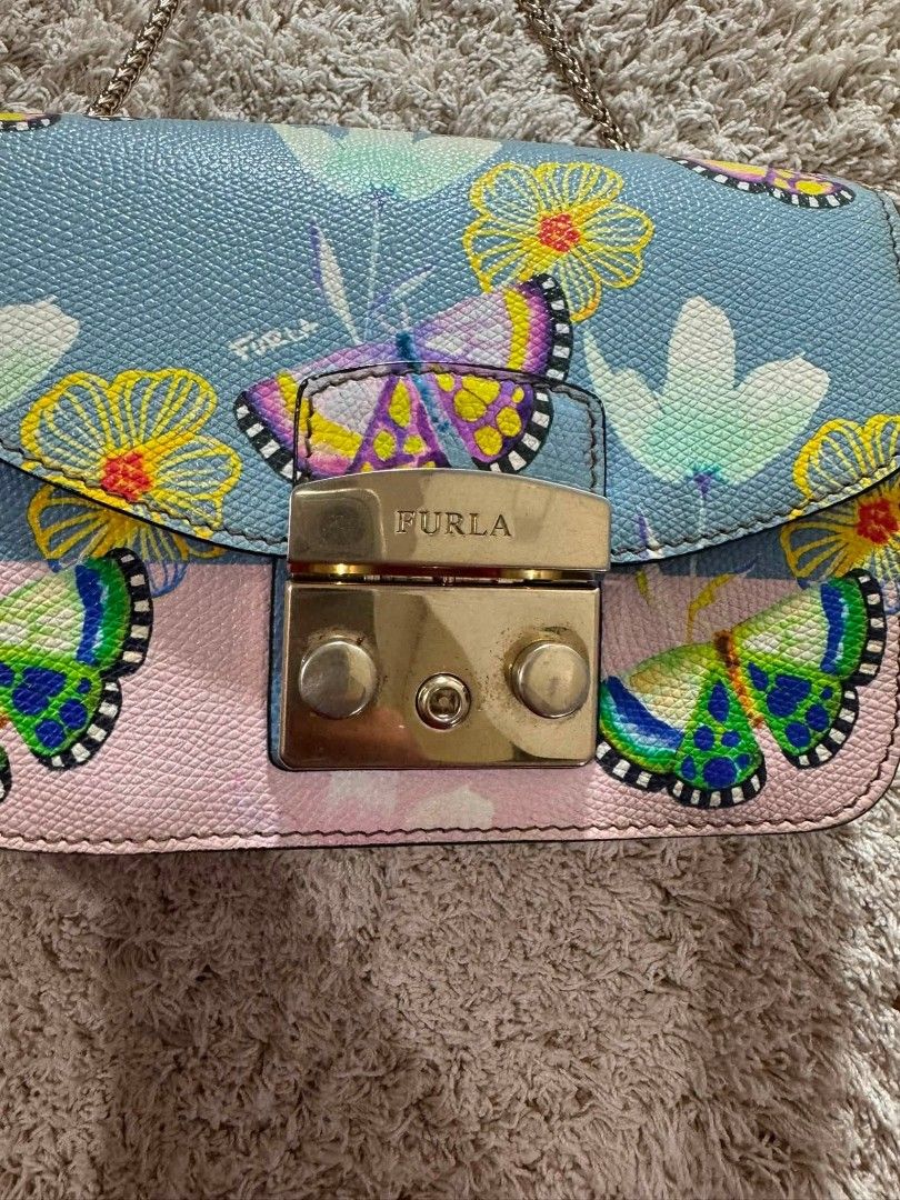 Furla Mini Butterfly Print Chain Bag (Category: Luxury Bags & Wallets) located in Manila. Submitted by shy177 (Listing ID 1461390544, Image 2). Description: - Cute Furla mini bag - Light blue and pink color palette - Features a charming butterfly and floral print - Elegant gold chain strap - Secure turn-lock closure - Ideal for evening events or adding a vibrant accent to any outfit - Compact and easy to carry.