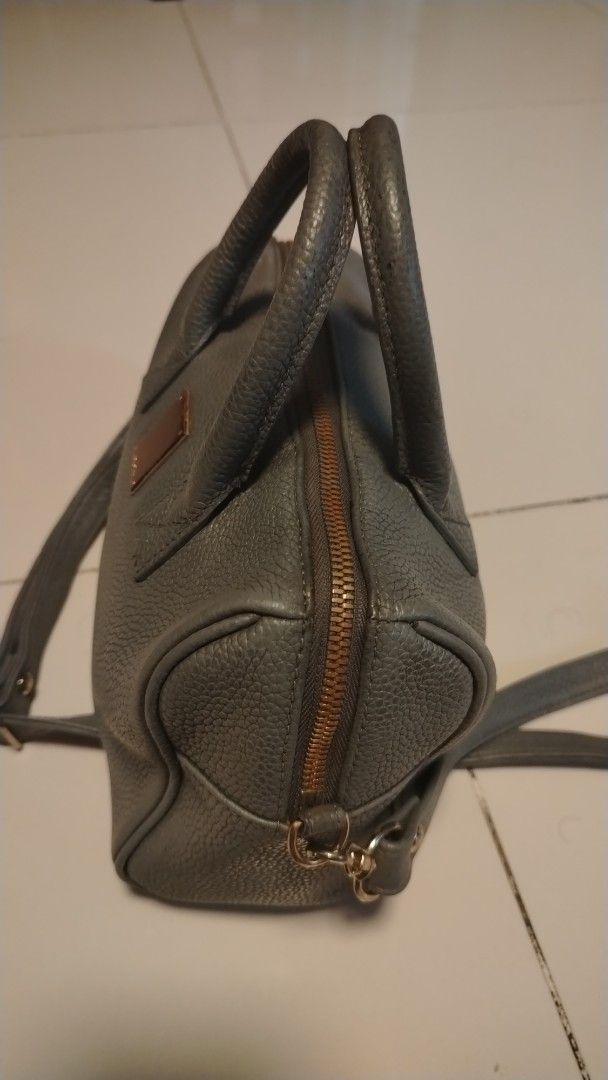Couronne Handbag with Shoulder Strap (Category: Shoulder Bags) located in Manila. Submitted by wildwind_73f77a (Listing ID 1461482129, Image 3). Description: - Grey leather satchel style handbag - Top handles and detachable shoulder strap - Zipper closure - Gold tone hardware with front metal plate - Textured leather finish - Spacious interior for essentials - Ideal everyday bag.