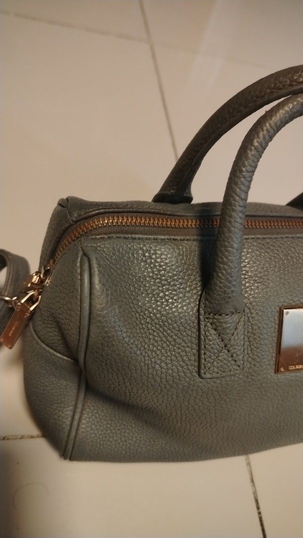 Couronne Handbag with Shoulder Strap (Category: Shoulder Bags) located in Manila. Submitted by wildwind_73f77a (Listing ID 1461482129, Image 2). Description: - Grey leather satchel style handbag - Top handles and detachable shoulder strap - Zipper closure - Gold tone hardware with front metal plate - Textured leather finish - Spacious interior for essentials - Ideal everyday bag.