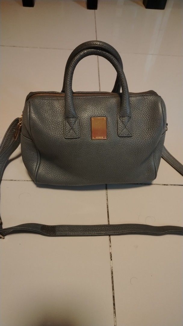 Couronne Handbag with Shoulder Strap (Category: Shoulder Bags) located in Manila. Submitted by wildwind_73f77a (Listing ID 1461482129, Image 1). Description: - Grey leather satchel style handbag - Top handles and detachable shoulder strap - Zipper closure - Gold tone hardware with front metal plate - Textured leather finish - Spacious interior for essentials - Ideal everyday bag.