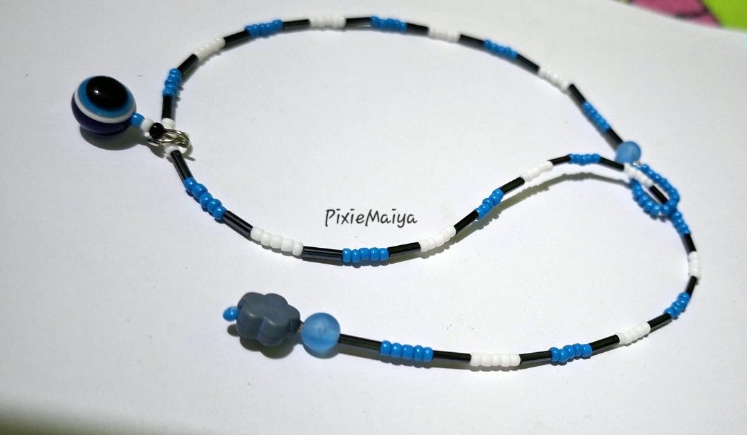 Handmade Beaded Necklace with Evil Eye Charm (Category: Necklaces) located in Valenzuela. Submitted by pixieworks64309 (Listing ID 1461505682, Image 1). Description: - Cute handmade beaded necklace - Features blue, white, and black beads - Adorned with an evil eye charm on one side and a cloud charm on the other - Secure toggle clasp - Perfect for adding a unique pop of color to any outfit.