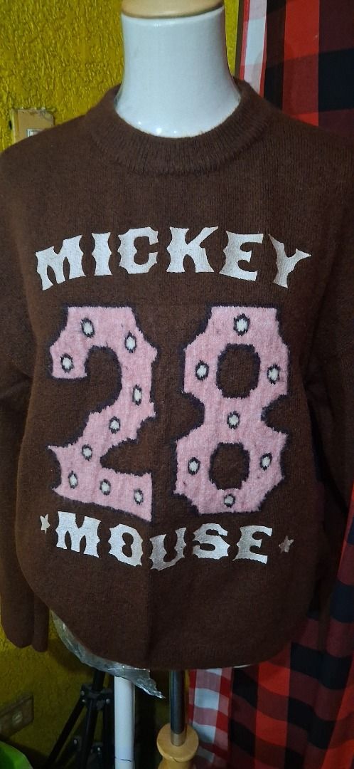 H&M Disney Collection Mickey Mouse 28 Sweater (Category: Longsleeves) located in Manila. Submitted by katkween23 (Listing ID 1461463772, Image 3). Description: - Cozy brown knit sweater - Features Mickey Mouse and '28' graphic - Part of the 2025 CNY Disney Collection - Long sleeves and crew neck design - Ideal for Disney enthusiasts - Versatile for pairing with jeans or skirts.