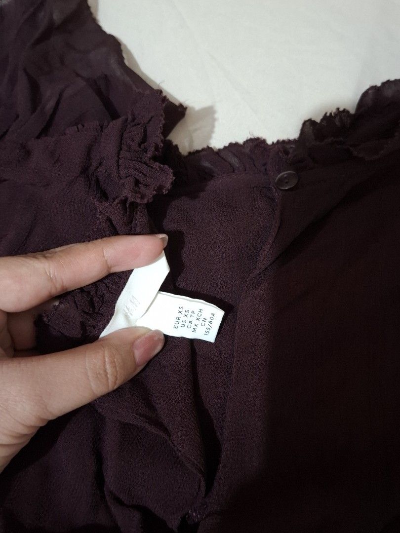 H&M Sheer Ruffle Top XS Plum Maroon (Category: Sleeveless) located in Taguig. Submitted by plnmrtz (Listing ID 1461522856, Image 2). Description: - Sheer plum purple top from H&M - Features ruffled neckline and hem - Shirred bust detail for a flattering fit - Short sleeves - Button closure at the back - Lightweight fabric, perfect for layering or warm weather - Worn only once - RFS: Decluttering .