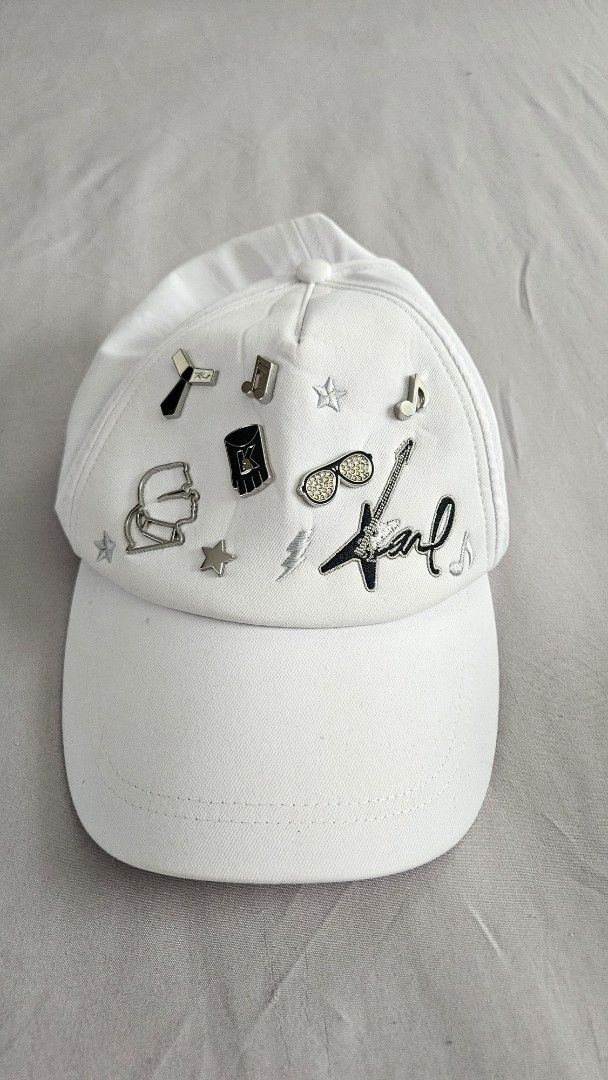 Karl Lagerfeld White Cap with Charms (Category: Hats & Beanies) located in Rizal. Submitted by vanbdc24 (Listing ID 1461379525, Image 1). Description: - bought $120 authentic Karl Lagerfeld cap - Features unique charms: sunglasses, guitar, tie - Adjustable strap for a perfect fit - Interior black band with Karl Lagerfeld branding - Adds a stylish flair to any outfit.