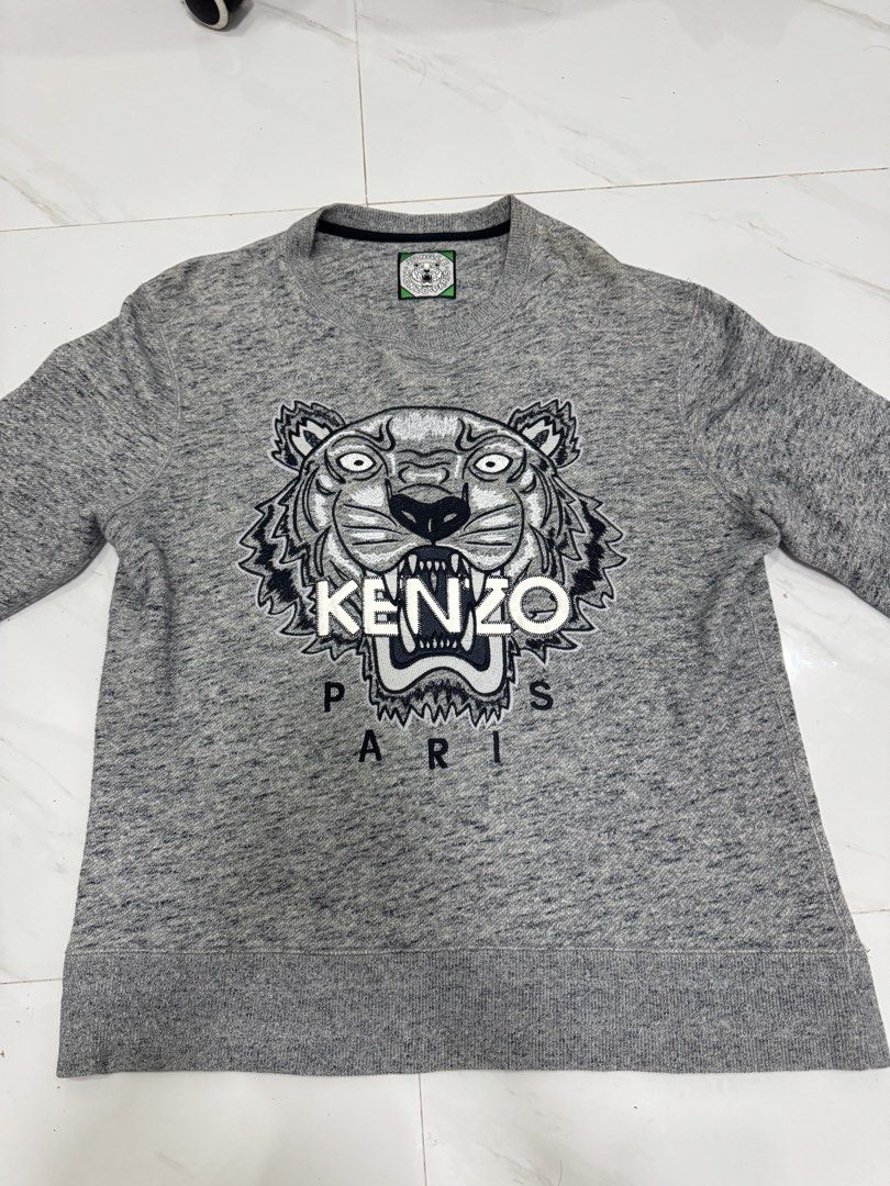 Kenzo Paris Tiger Logo Grey Sweatshirt (Category: Coats, Jackets and Outerwear) located in Manila. Submitted by yelutot (Listing ID 1461545756, Image 2). Description: - Grey Kenzo sweatshirt - Features iconic tiger logo - 'KENZO PARIS' text below graphic - Long sleeves - Crew neck - Ideal for comfortable and stylish casual wear.
