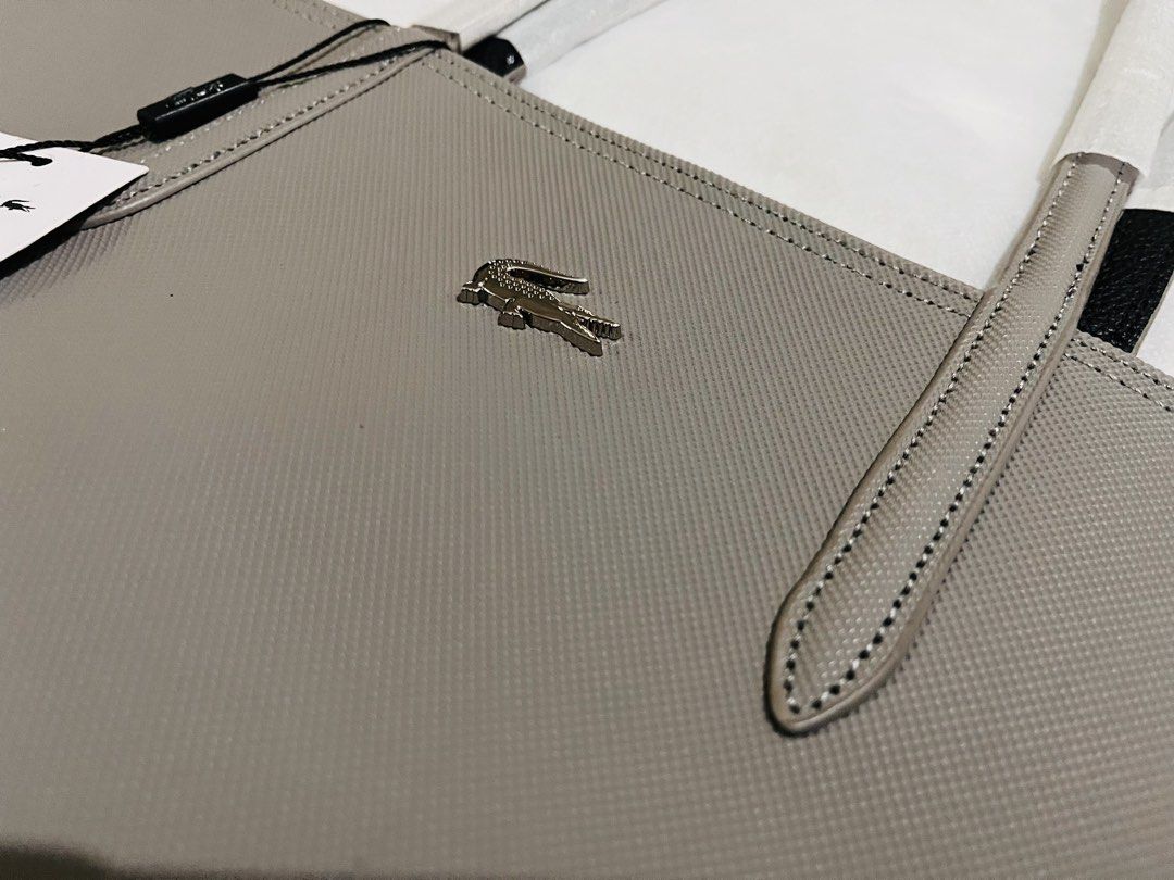Lacoste Grey Tote Bag with Tag (Category: Tote Bags) located in Manila. Submitted by pickleball_paddles (Listing ID 1461441525, Image 2). Description: - Authentic Lacoste grey tote bag - Features the iconic crocodile logo on the front - Comes with original tags attached - Interior is black with a convenient zippered compartment - Stylish white and black handles - Ideal for everyday use.