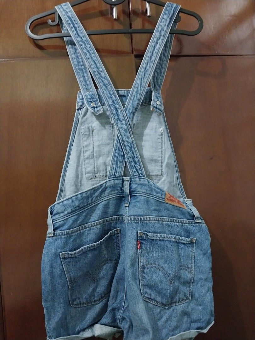 Levi's Denim Short Overalls (Category: Jumpsuits) located in Aroroy. Submitted by imeea (Listing ID 1461432390, Image 2). Description: - Classic Levi's denim short overalls - Light wash with distressed details - Adjustable straps - Button closures on the sides - Two front and two back pockets - Rolled hem shorts - Ideal for a casual, laid-back look.