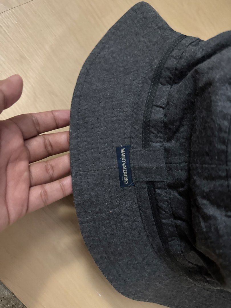 Mario Valentino Bucket Hat 🇯🇵 (Category: Hats & Beanies) located in Manila. Submitted by juhjuh (Listing ID 1461380170, Image 3). Description: - Mario Valentino dark grey bucket hat - Small - Made from a textured fabric - Simple, versatile design perfect for everyday wear - Features a small brand name tag - Please check photos for detailed condition.