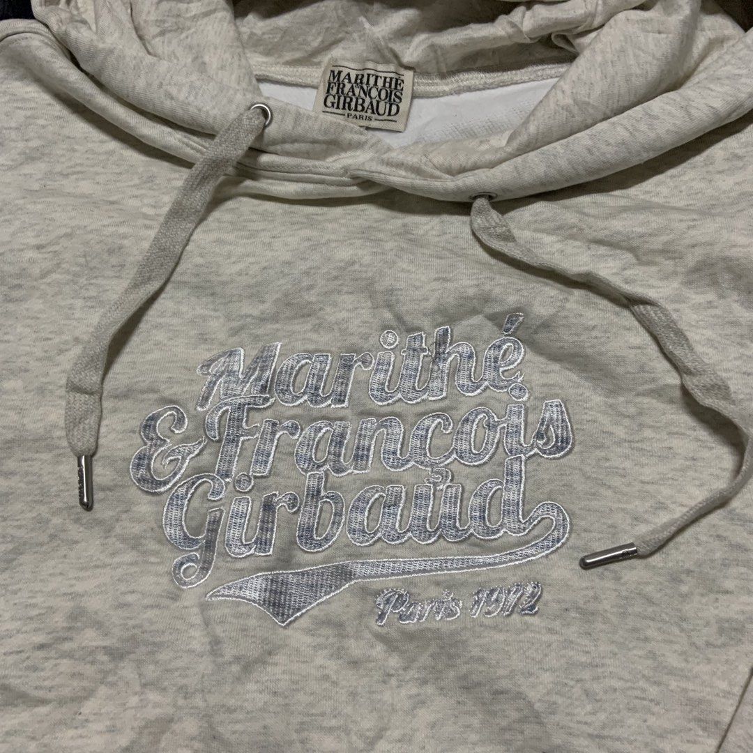 Marithe Francois Girbaud Paris 1972 Hoodie Size S (Category: Coats, Jackets and Outerwear) located in Compostela. Submitted by anyastark (Listing ID 1461382152, Image 2). Description: - Marithe Francois Girbaud hoodie - Color: Light grey marl - Size: Tagged S - Features: Embroidered brand name and 'Paris 1972' on front, drawstring hood with metal tips, kangaroo pocket - Material: Cotton blend - Dirt Stain Washable - Width 22 - Length 26.