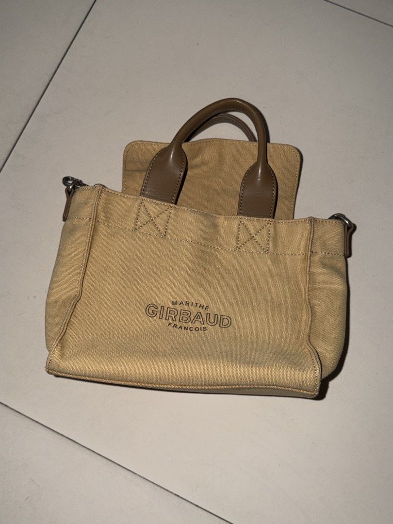 Marithe Girbaud Canvas Handbag (Category: Luxury Bags & Wallets) located in Manila. Submitted by hatdognablue (Listing ID 1461360888, Image 2). Description: - Marithe Girbaud canvas handbag - Tan color with brown leather accents - Top handles and adjustable crossbody strap - Front zip pocket for quick access - Spacious main compartment - Interior zip pocket for essentials - Ideal for everyday use.