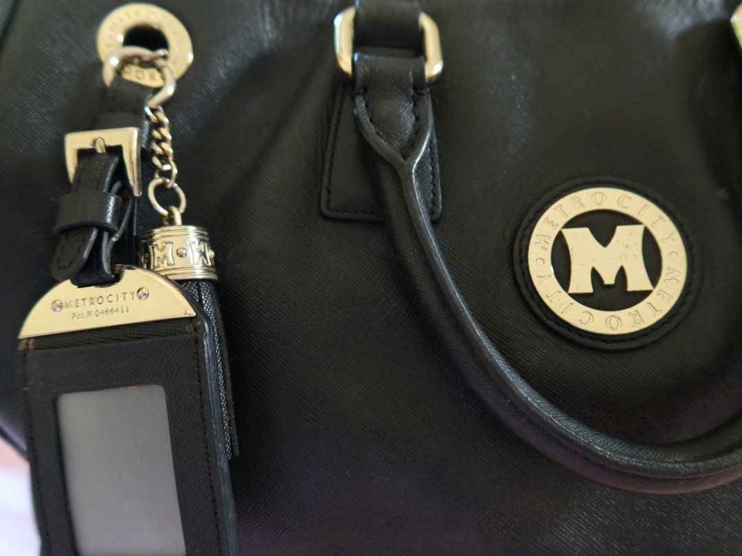 METROCITY Black Leather Satchel Handbag (Category: Shoulder Bags) located in Pasig City. Submitted by simplylizzy (Listing ID 1461336483, Image 2). Description: - METROCITY black leather satchel bag - Secure top zip closure - Multiple interior compartments for organization - Detachable ID holder and tassel charm included - Stylish gold hardware details - Spacious design for daily essentials.