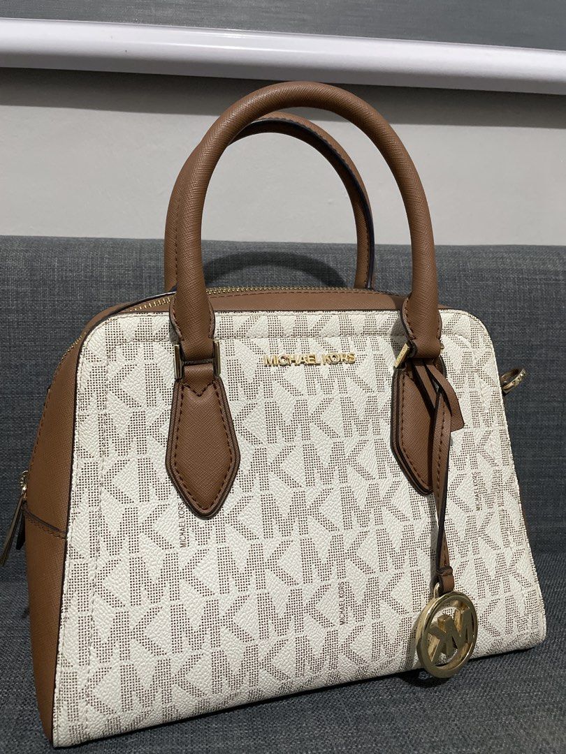 Michael Kors Monogram Satchel Bag with Strap (Category: Luxury Bags & Wallets) located in Pasig City. Submitted by roseyyylife (Listing ID 1461454246, Image 2). Description: - Authentic Michael Kors monogram satchel - Signature MK print in vanilla and brown - Elegant gold hardware details - Features a secure top zip closure - Comes with a detachable shoulder strap for versatile carrying - Note: Small pink mark visible on the underside - Ideal for