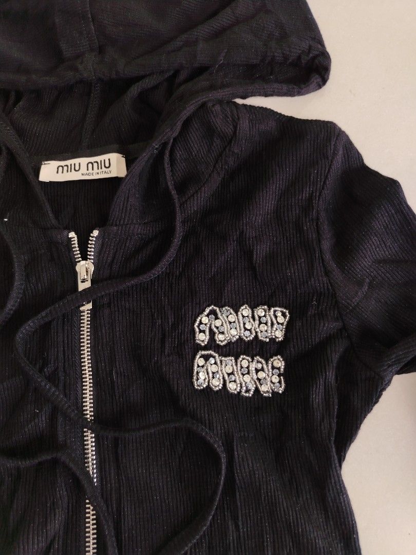 Miu miu (Category: Coats, Jackets and Outerwear) located in Don Carlos. Submitted by thriftnidodong_23 (Listing ID 1461386619, Image 3). Description: This is a black ribbed Miu Miu zip-up hoodie featuring a sparkly rhinestone logo detail on the chest.