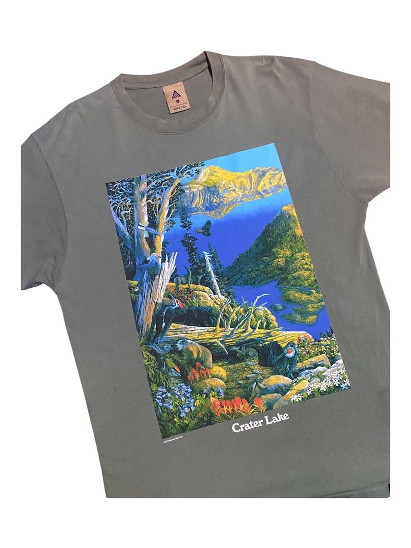 Nike ACG Oregon Lake (Category: Tshirts & Polo Shirts ) located in Manila. Submitted by bapekiddos (Listing ID 1461494101, Image 3). Description: - Grey t-shirt with a vibrant, detailed graphic print of Crater Lake, Oregon. - Front design: 'Crater Lake' - Back design: 'Oregon' - Brand: All Conditions Gear 2021 - Estimated Size: Medium (based on tag) - Ideal for nature enthusiasts and fans of Oregon. - High-quality, colorful print. -21x28 -verygoo