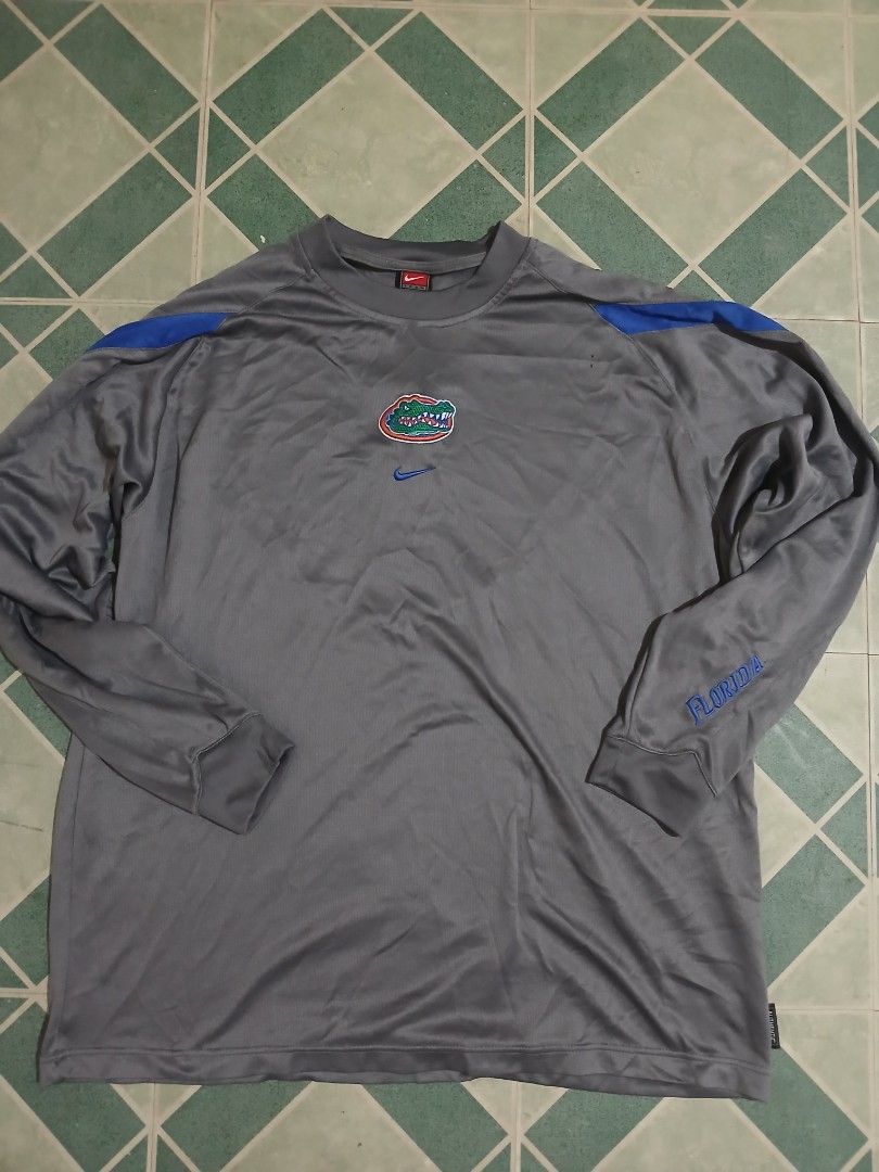 Nike Florida Gators Long Sleeve Shirt (Category: Tshirts & Polo Shirts ) located in Pateros City. Submitted by m4ry.b0o (Listing ID 1461453962, Image 1). Description: - Grey long-sleeved shirt - Features Florida Gators logo and Nike swoosh - Blue accents on shoulders - 'Florida' text on sleeve - Made with performance fabric - Ideal for any Gators fan.