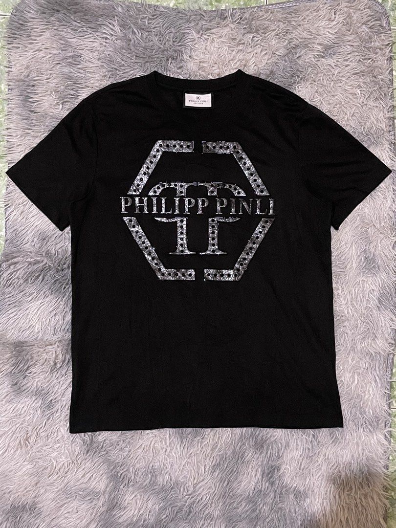 Philipp Plein Black T-Shirt with Hexagonal Logo (Category: Tshirts & Polo Shirts ) located in Manila. Submitted by khen23_408 (Listing ID 1461544962, Image 1). Description: - Authentic Philipp Plein black t-shirt - Size 56 - Iconic hexagonal PP logo with silver embellishments - Comfortable fabric - Ideal for casual wear or making a statement - Check label for material details.