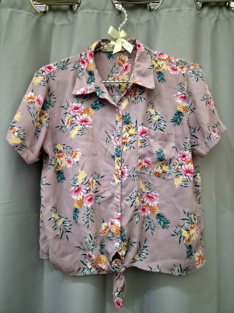 Pink Floral Pineapple Tie Front Button Up Shirt (Category: Shirts) located in Manila. Submitted by manoygoodies (Listing ID 1461401632, Image 1). Description: - Adorable pink shirt with a fun floral and pineapple print. - Features short sleeves and a classic collared neckline. - Stylish tie-front detail at the hem. - Ideal for a casual, summery look. - Easily pairs with shorts or jeans for versatile styling..