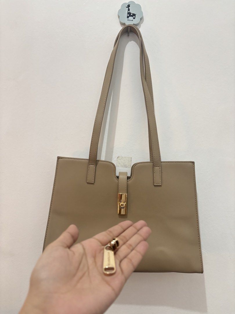 Preloved MOSSDOOM Tote Bag Beige (Category: Tote Bags) located in Zamboanga. Submitted by silverfrost (Listing ID 1461359663, Image 2). Description: BRAND: MOSSDOM - Color: Taupe - Functional bag with double lock clasp, however sira main zipper inside, pwede naman ipaayos - Interior: Zippered pockets and compartments - Straps: Comfortable for shoulder wear - Perfect for daily use & good size for travel - has signs of usage, but still functional &