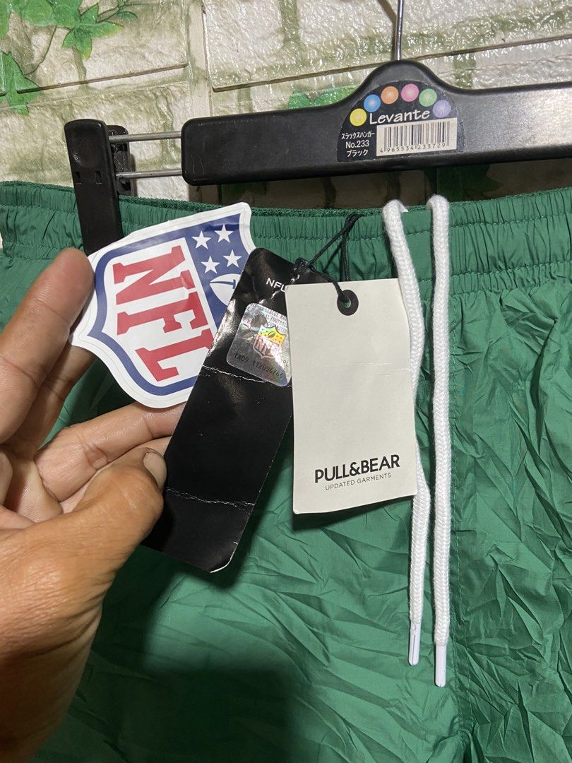 Pull & Bear NFL New York Jets Green Shorts (Category: Shorts) located in Davao. Submitted by mengsmixitems (Listing ID 1461340418, Image 3). Description: - Brand: Pull & Bear - Color: Green - Design: Features New York Jets NFL logo on the leg - Fit: Drawstring waist for adjustable comfort - Usage: Ideal for casual wear or sports activities - Style: Team apparel shorts.