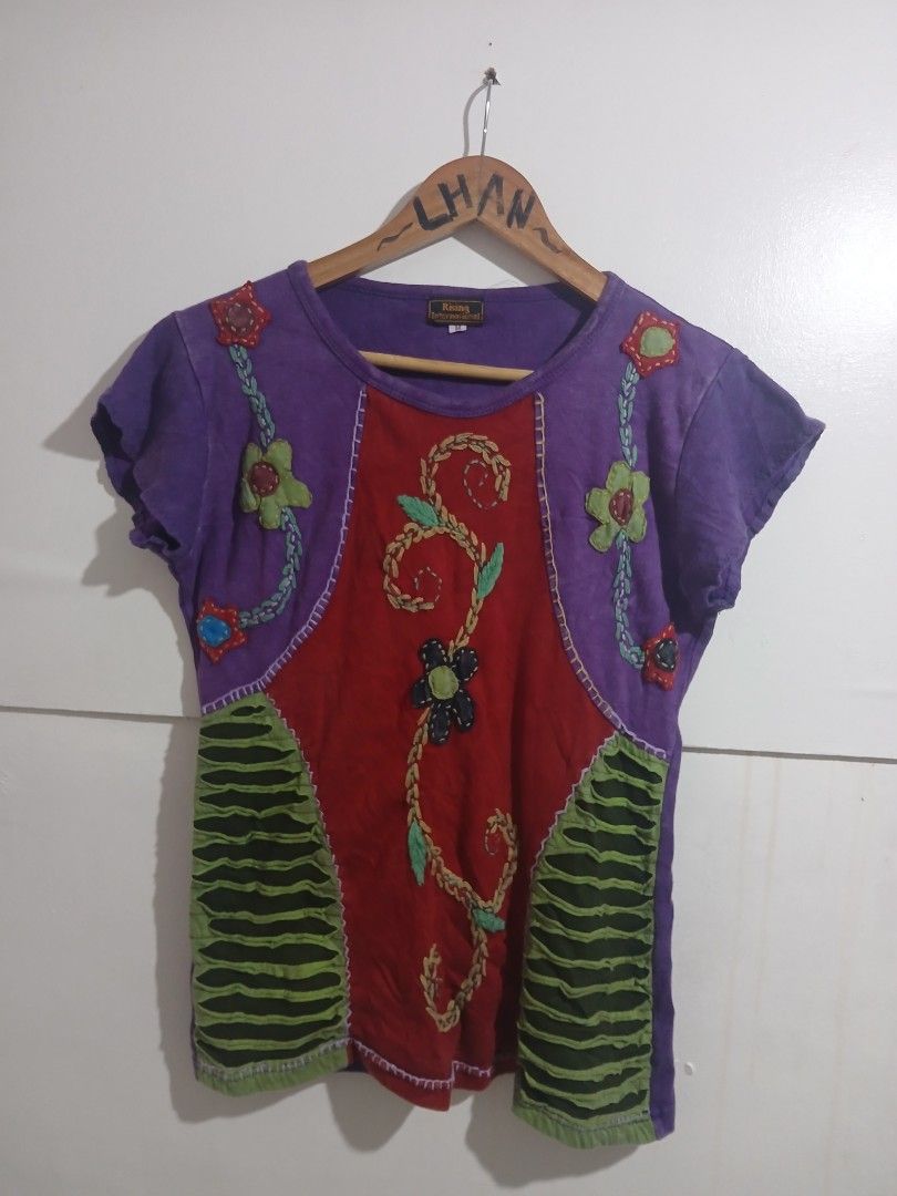 Rising International Patchwork Embroidered T-shirt Size M (Category: Tshirts & Polo Shirts ) located in Taguig. Submitted by thriftnilhan (Listing ID 1461391511, Image 1). Description: - Unique patchwork design from Rising International. - Eye-catching red center panel with embroidered vines and a black flower. - Vibrant purple sleeves and sides adorned with floral appliques. - Contrasting green ribbed panels on the sides for added detail. - Size