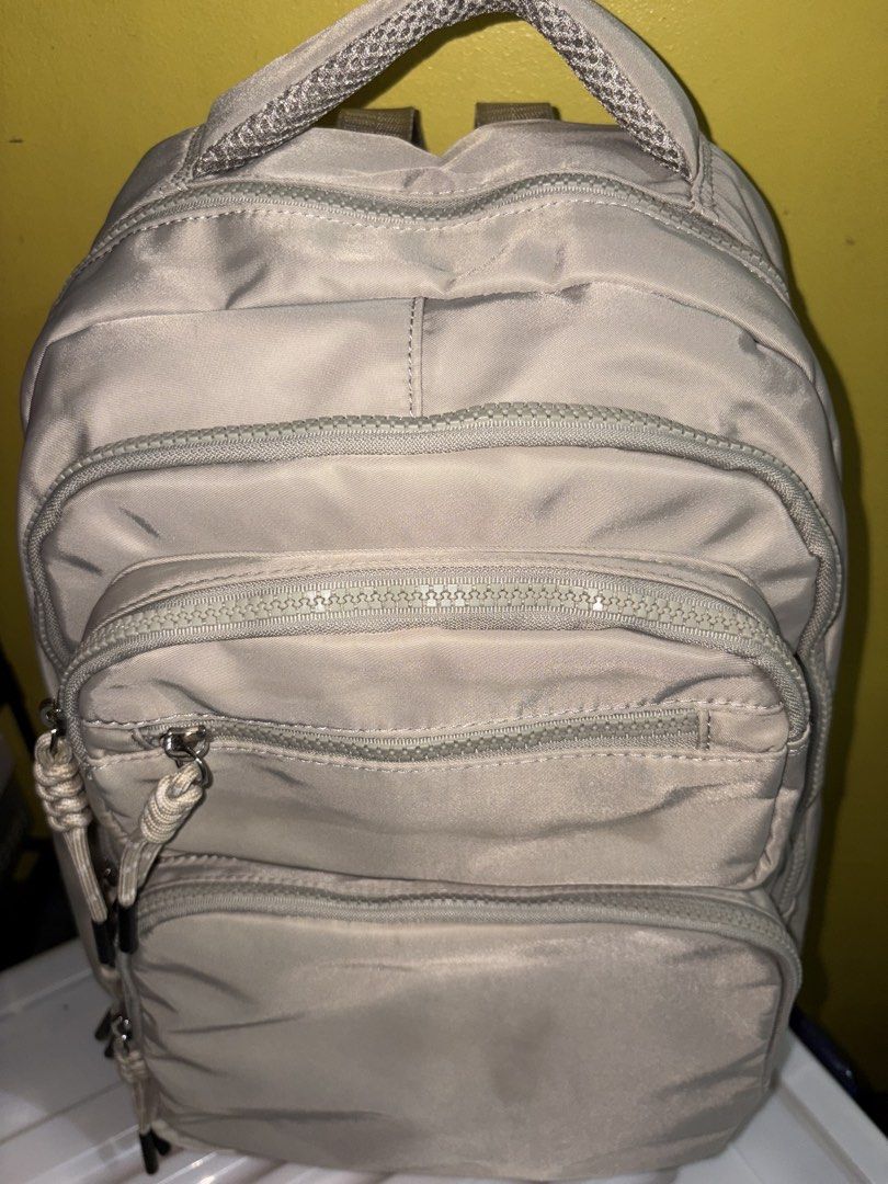 Light Beige Nylon Backpack with Multiple Zipped Pockets (Category: Backpacks) located in Manila. Submitted by cleverwater2528 (Listing ID 1461480880, Image 2). Description: - Light beige nylon backpack (with slight stain visible in the picture) - Main compartment - Front zipped pockets - Small top front zipped pocket - Adjustable straps with rope pull tabs - Ideal for everyday use or travel PRICE IS STILL NEGOTIABLE.