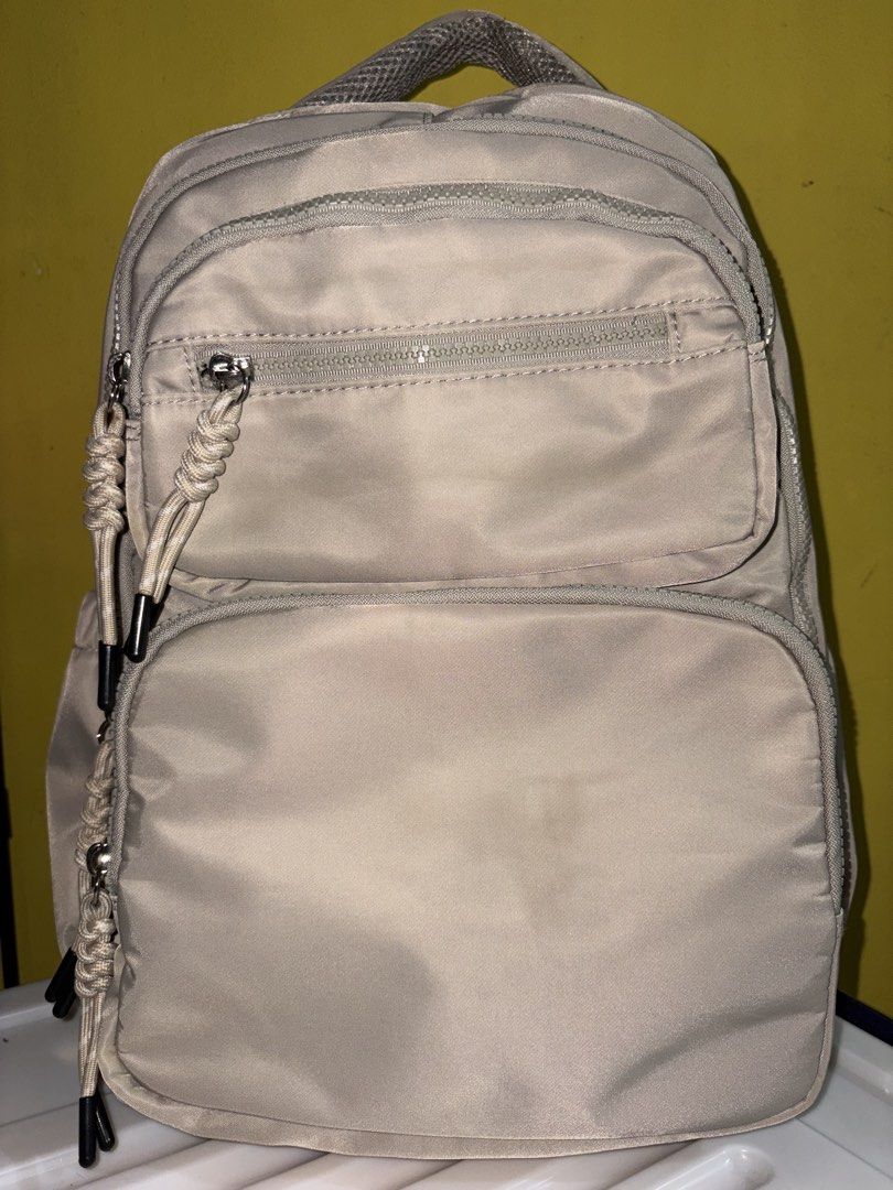 Light Beige Nylon Backpack with Multiple Zipped Pockets (Category: Backpacks) located in Manila. Submitted by cleverwater2528 (Listing ID 1461480880, Image 1). Description: - Light beige nylon backpack (with slight stain visible in the picture) - Main compartment - Front zipped pockets - Small top front zipped pocket - Adjustable straps with rope pull tabs - Ideal for everyday use or travel PRICE IS STILL NEGOTIABLE.