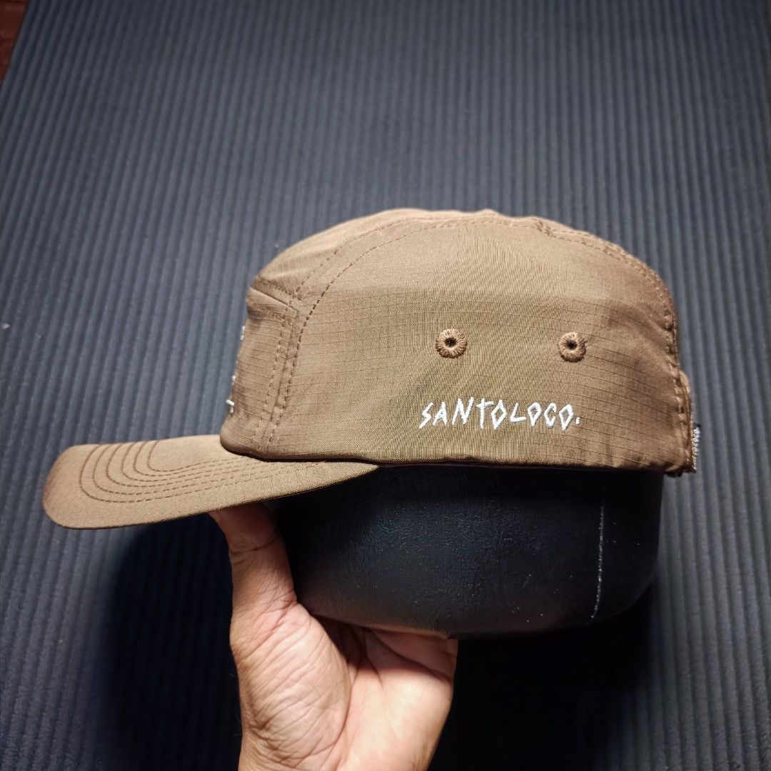 SANTOLOCO 5 Panel Cap skate & surf apparel (Category: Caps & Hats) located in Manila. Submitted by nye.seller (Listing ID 1461494545, Image 2). Description: - Brand: SANTOLOCO - Style: 5-panel cap - Color: Brown - Design: Embroidered skateboard graphic on front - Features: Adjustable strap at the back for a custom fit - Material: Durable, ripstop-like fabric - Ideal for: Everyday wear.