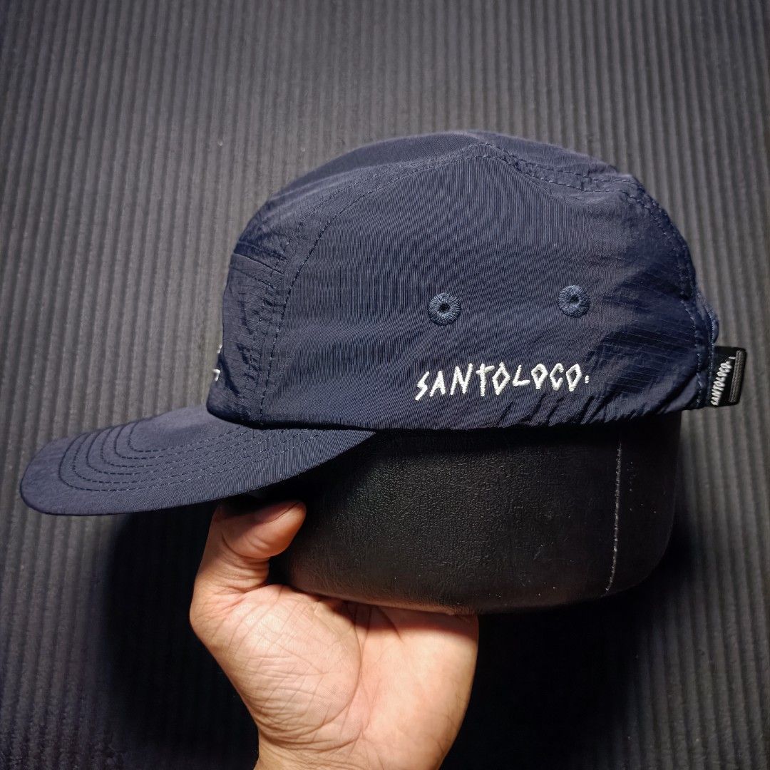 Santoloco 5 Pannel skate & surf (Category: Caps & Hats) located in Manila. Submitted by nye.seller (Listing ID 1461494012, Image 2). Description: - Brand: Santoloco - Skate & surf apparel - Color: Navy Blue - Style: 5-Panel Cap - Material: 100% Nylon - Features: Graphic design on front panel, embroidered logo on side - Fit: Adjustable strap at the back - Ideal for: Everyday wear.